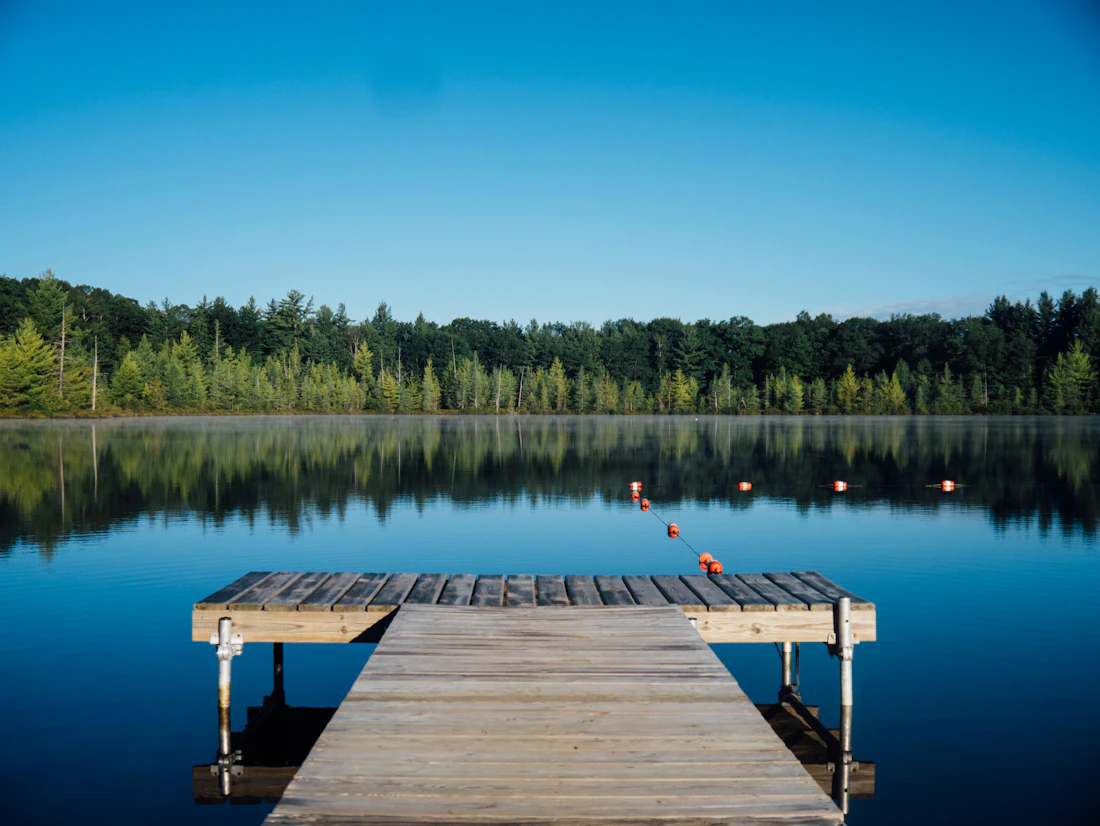 A wooden jetty reaching into still lake water