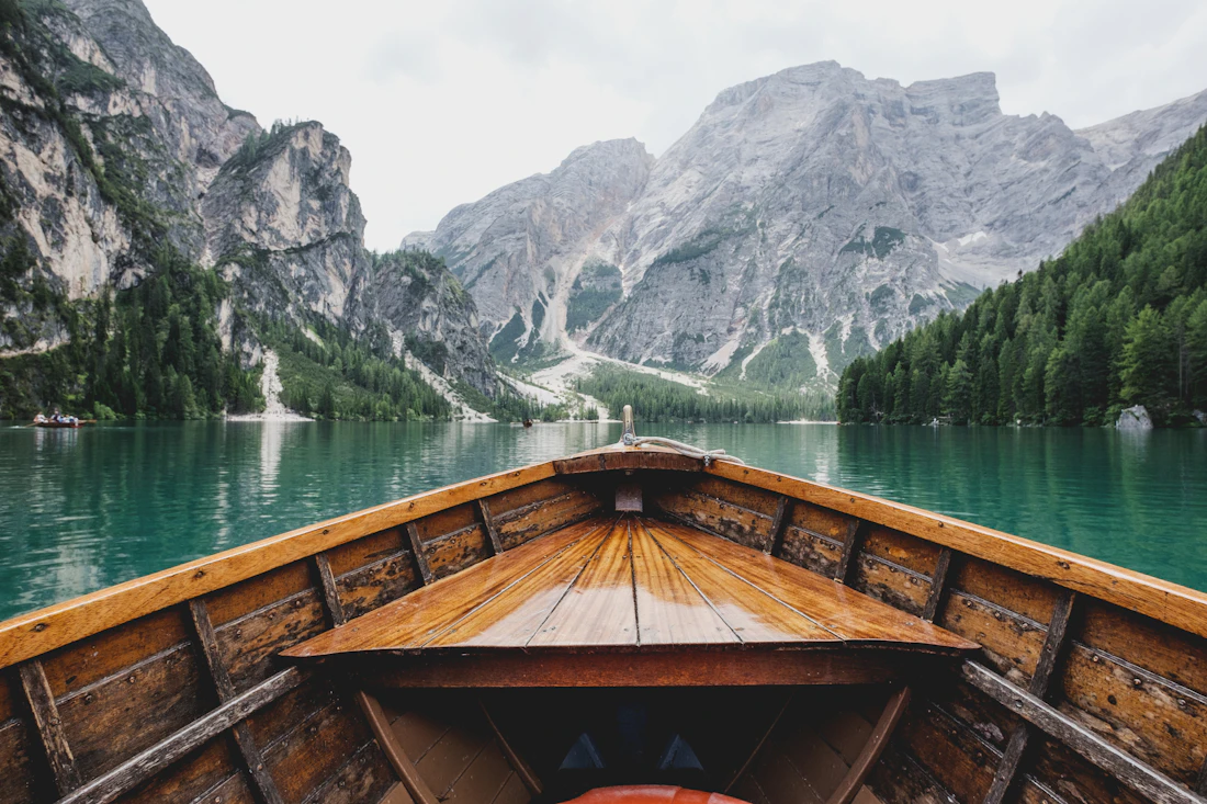 The bow of a wooden boat gliding toward the mountains