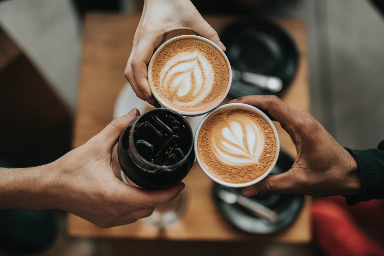 Two coffees held over a café table